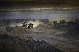 Trucks drive across dusty terrain